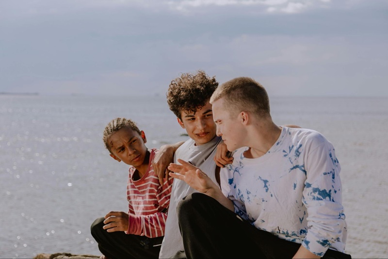 three teens sitting on a bear next to each other